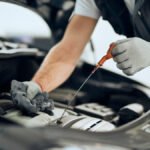 Close-up of car mechanic checking motor oil at repair shop.